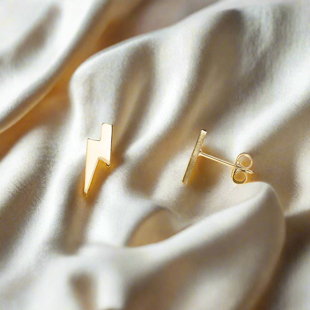 Gold lightning bolt earrings on a white background