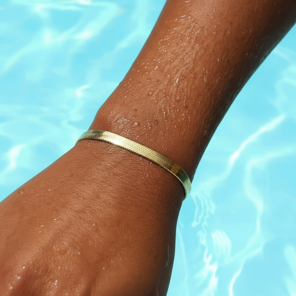 Gold bracelet on a wrist with a blue water background