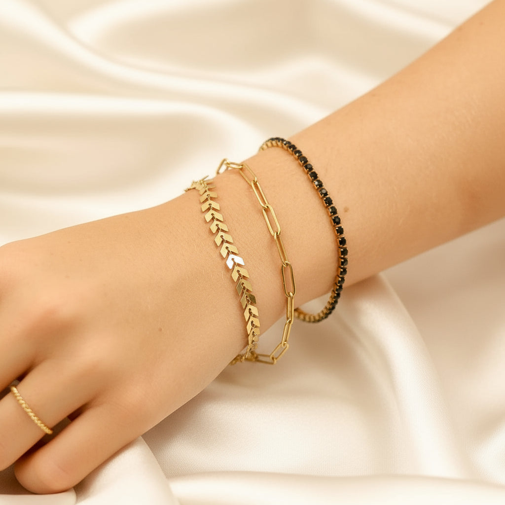 Close-up of a wrist wearing gold plated bracelets with a blurred background.