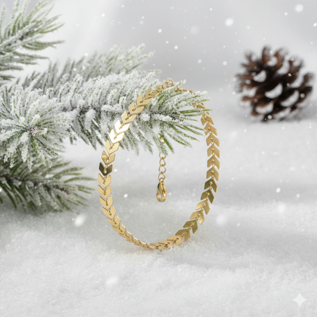 Gold plated bracelet on a snowy branch with pine cone