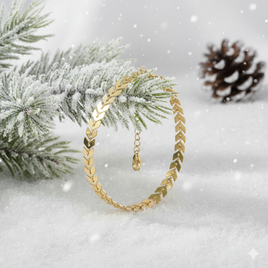Gold plated bracelet on a snowy branch with pine cone