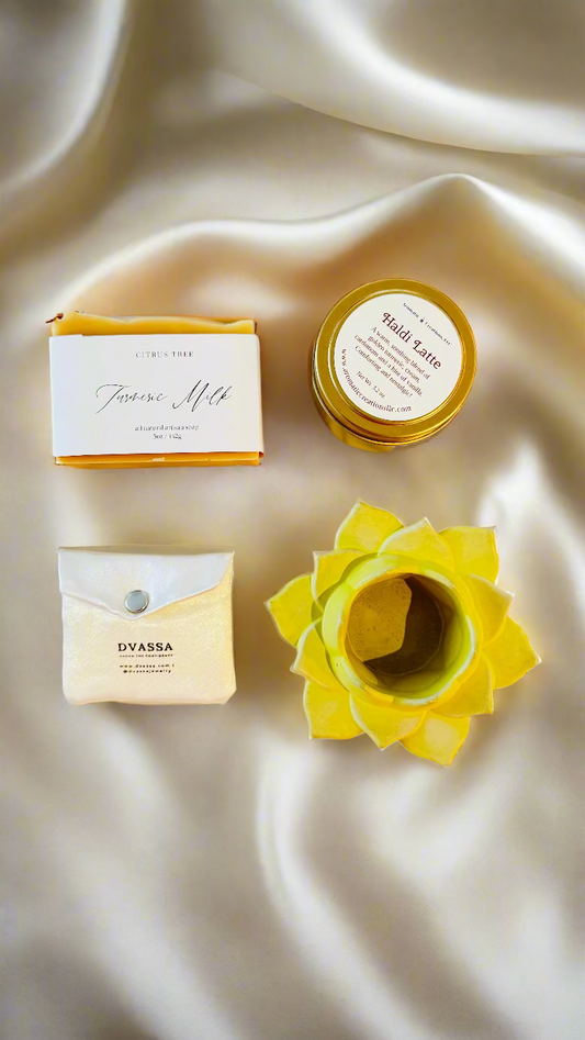 Collection of beauty products including a bar of soap, a jar, and a yellow flower-shaped container on haldi theme