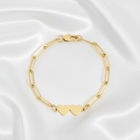 Gold bracelet with heart-shaped charm made up of stainless steel on a white background