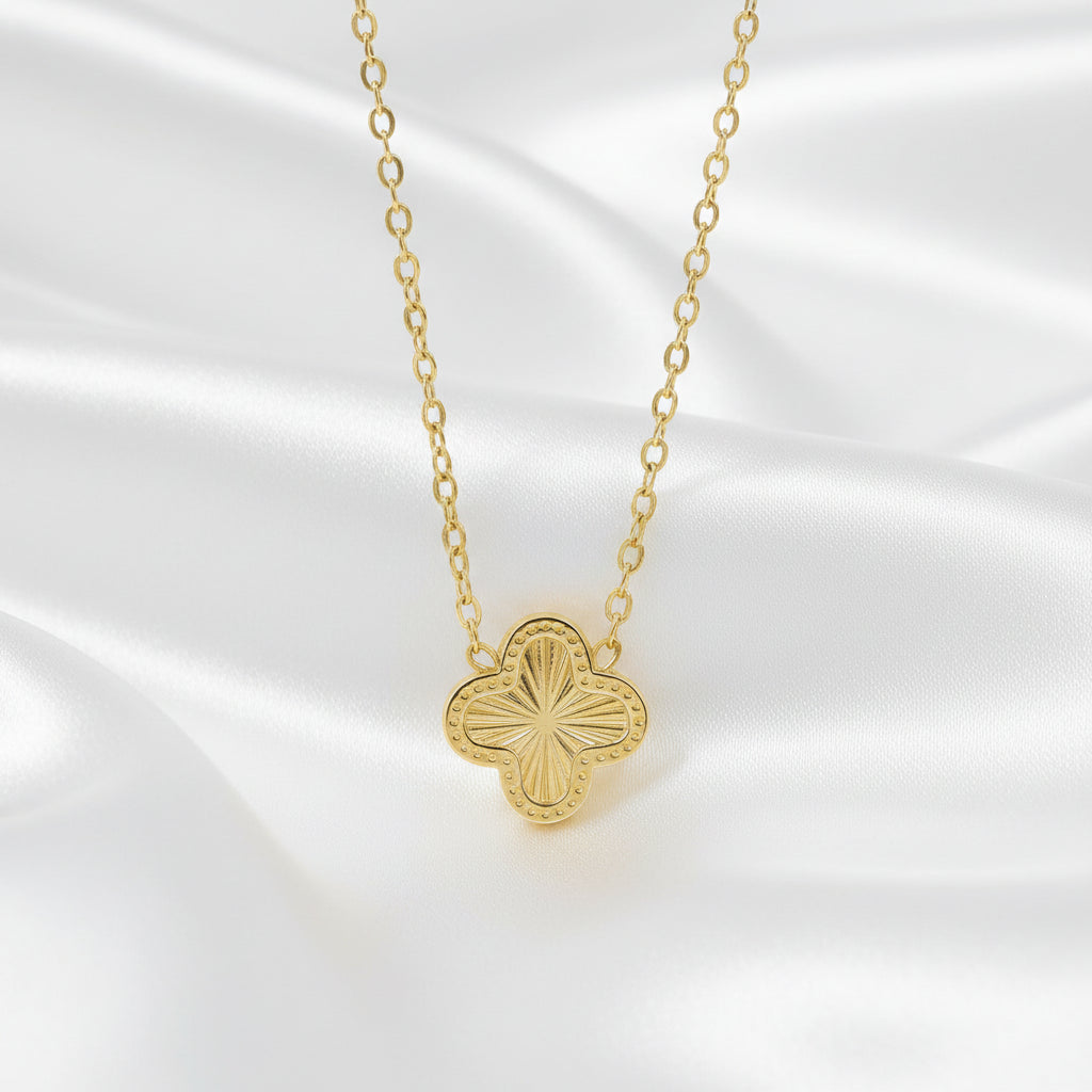 Gold necklace with a clover-shaped pendant on a white background