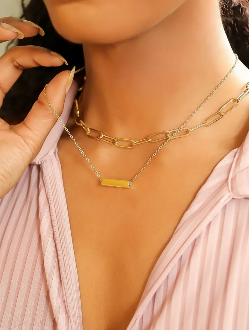 Close-up of a person wearing gold necklaces with a plain background