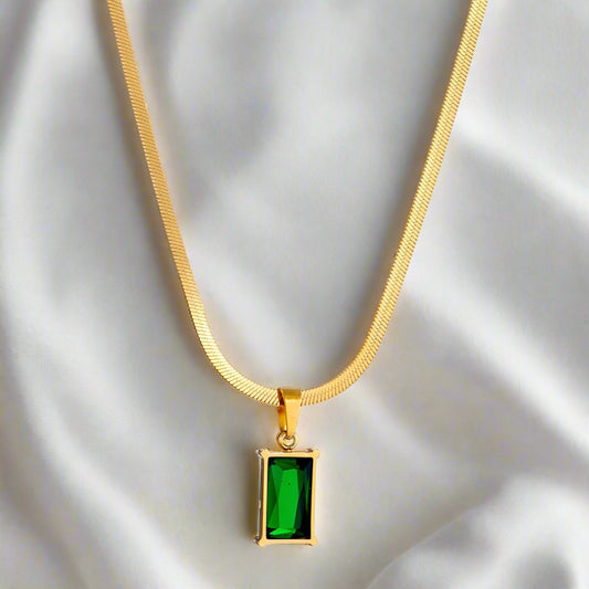 Gold necklace with a green emerald pendant on a white background