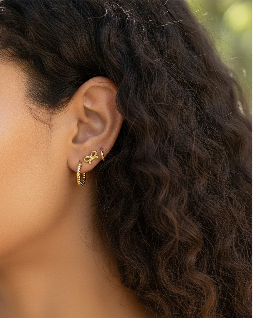 Close-up of a person wearing gold bow-shaped earrings from gold plated jewelry by dvassa
